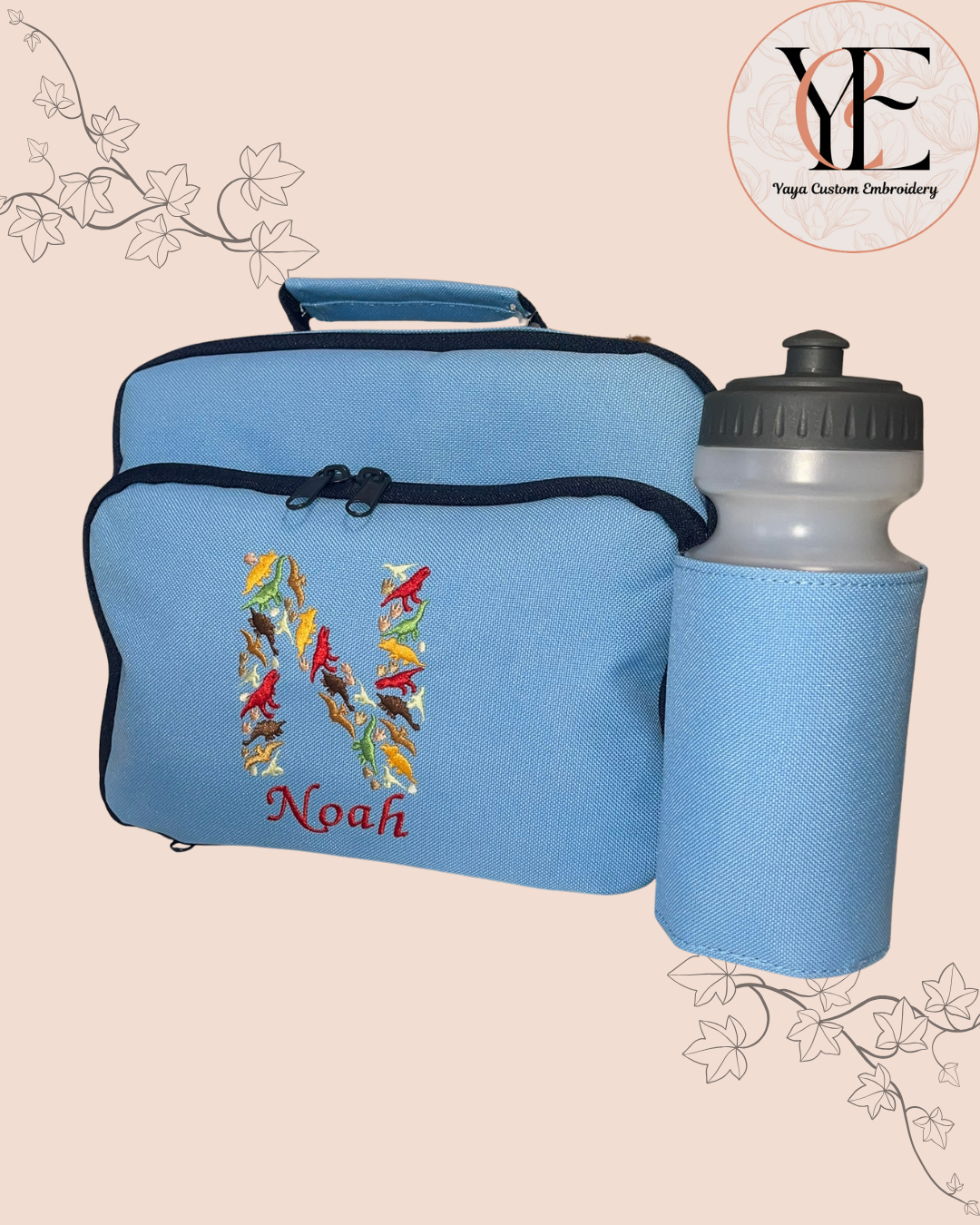 Blue insulated lunch bag with embroidered design and 'Noah' text, accompanied by a matching water bottle holder on a beige background.