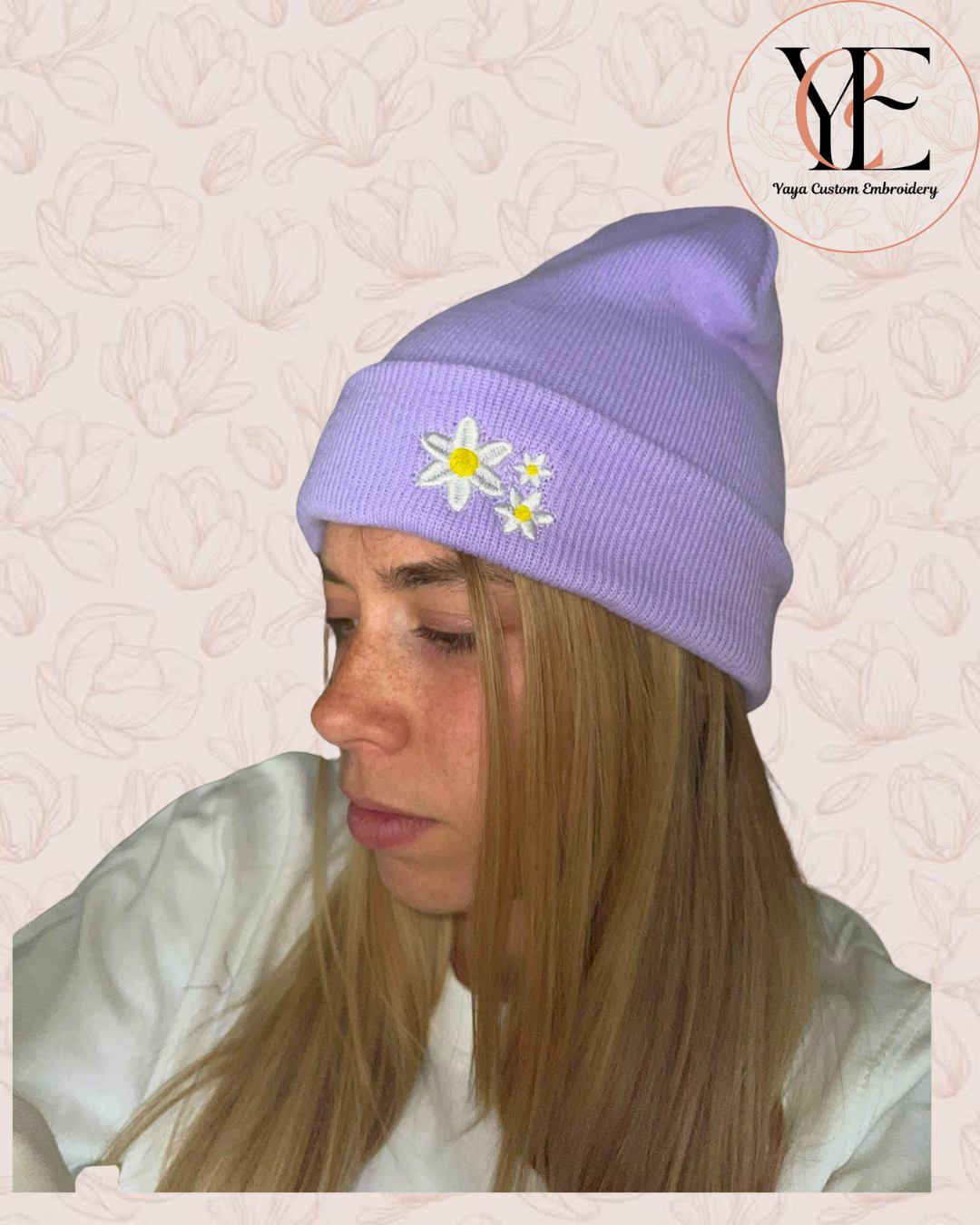 Person wearing a lavender beanie with floral designs on a textured light beige background