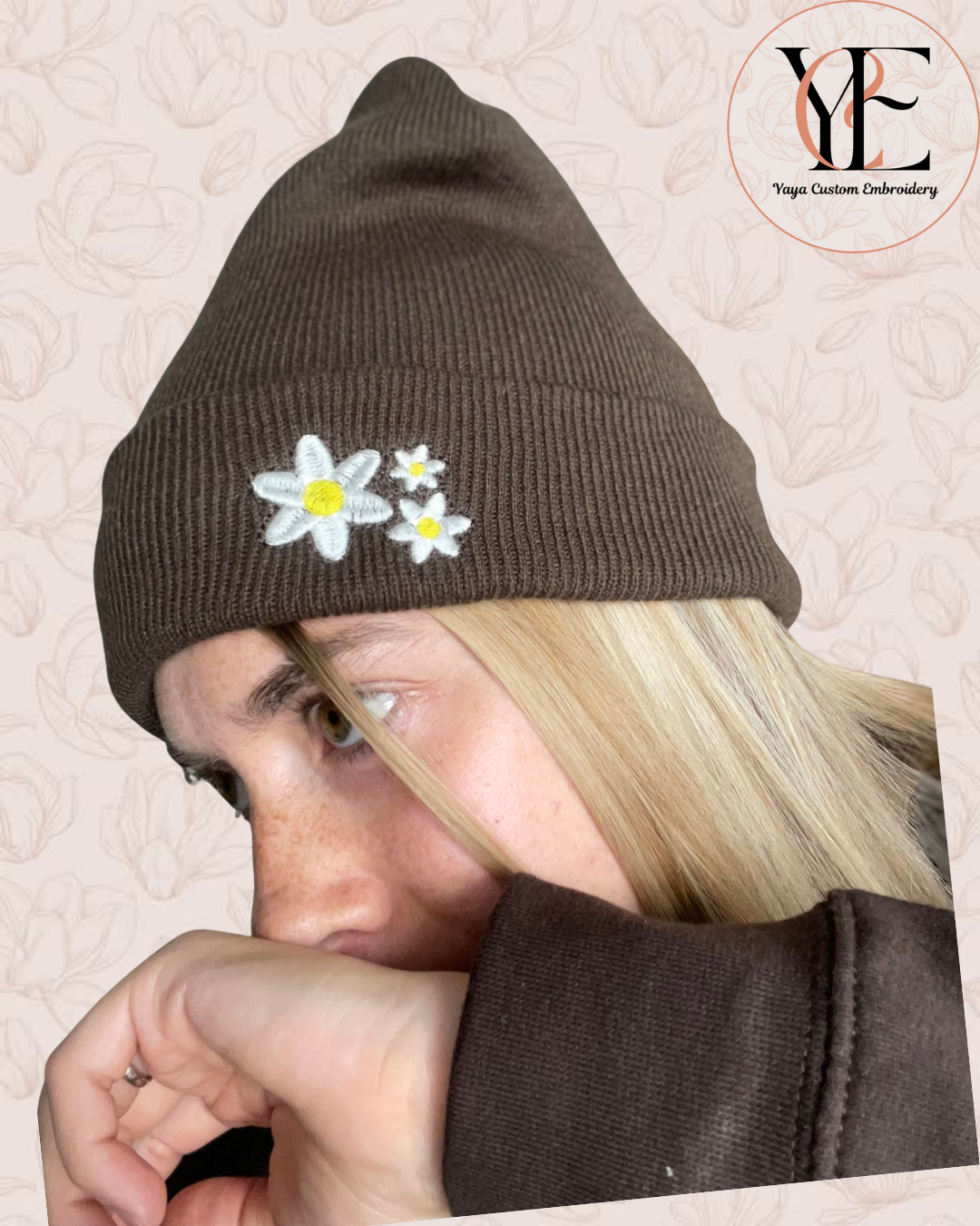 Person wearing a brown beanie with embroidered flowers on a beige background