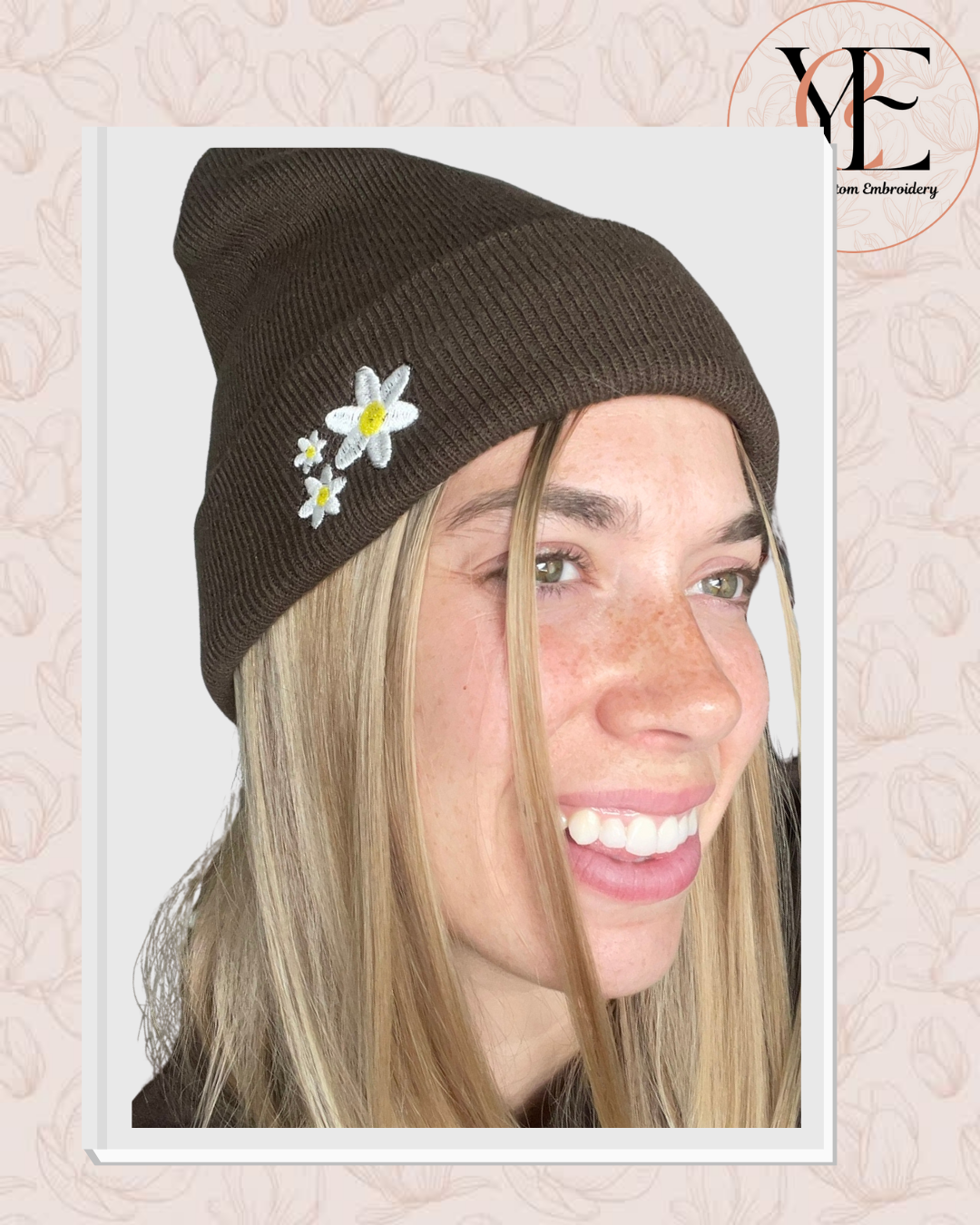 Person wearing a brown beanie with floral decorations on a light pink background