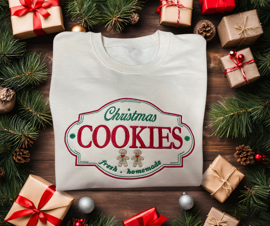 Folded up Christmas cookie label embroidered sweatshirt on a Christmas background with presents, pine cones, Christmas tree branches and Christmas balls.