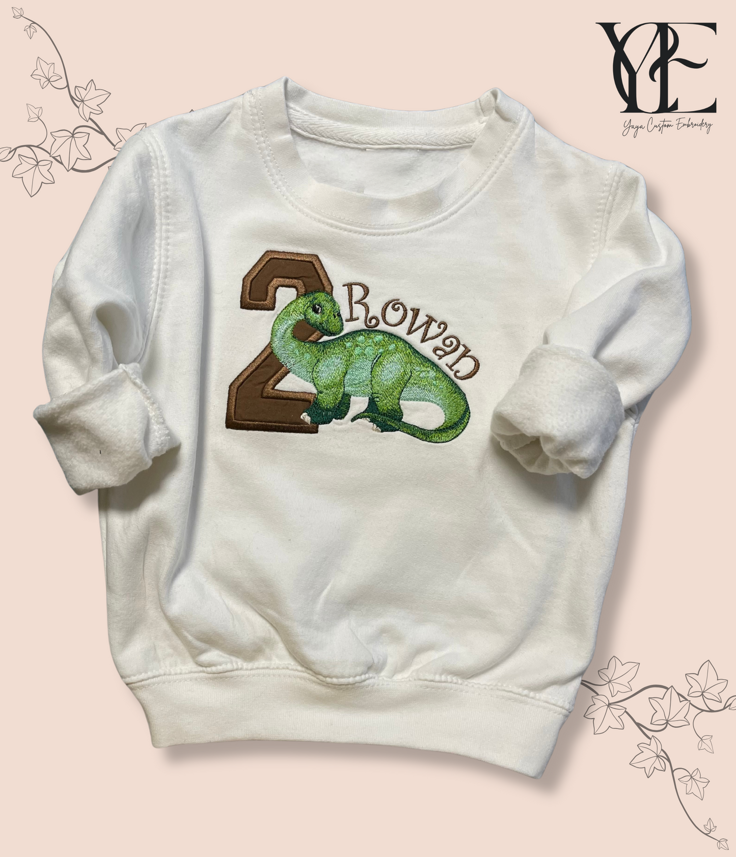 A white kids' sweatshirt with personalized Diplodocus embroidery and the kids' name on the front