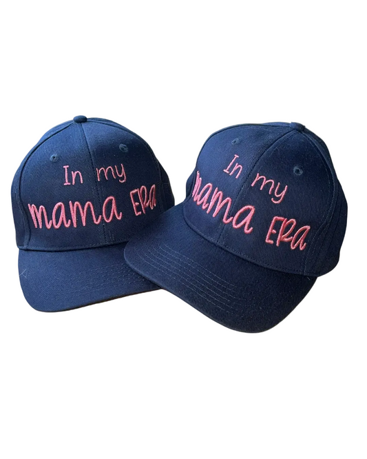 Two navy blue baseball caps with pink embroidered text reading 'In my mama EPA' on a white background.