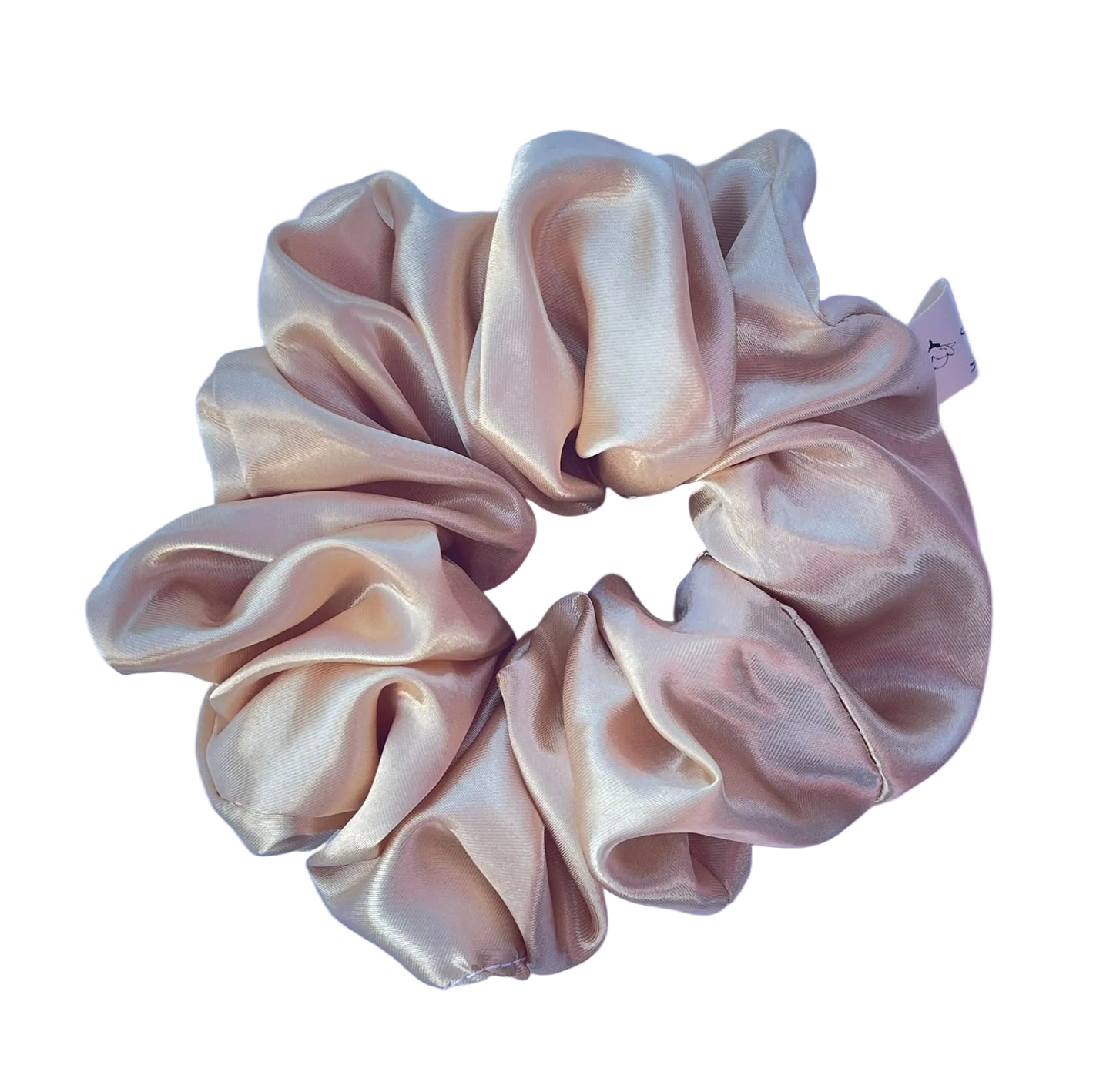 A single satin hair scrunchie in a light gold color, laid flat on a textured light purple background.
