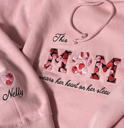 Close up image of the embroidery on the chest of the pink hoodie and the sleeve.