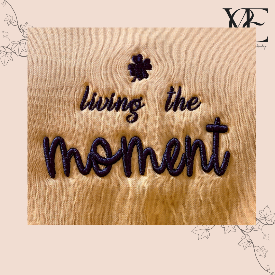 Close up of "living the moment" 3D embroidery in navy over an apricot colour