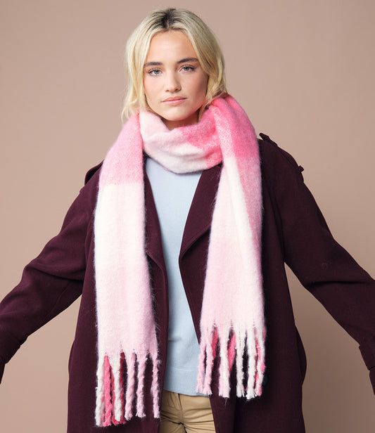 Woman wearing a pink check scarf and dark coat against a beige background